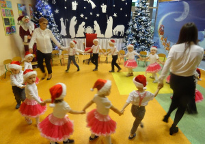 Pani dyrektor Maria Królikowska i pani Ewelina Cicha tańczą z dziećmi w kółeczku.